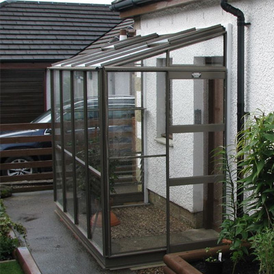 brown aluminium lean to greenhouse next to house