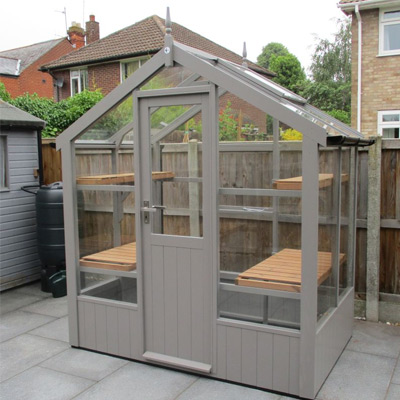 grey painted wooden greenhouse on patio