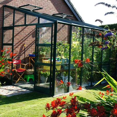 large black lean to greenhouse in garden with plants growing