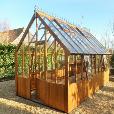 large light brown wooden greenhouse with victorian glazing