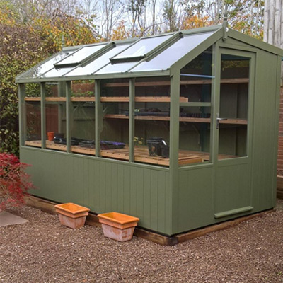 large green wooden potting shed in garden