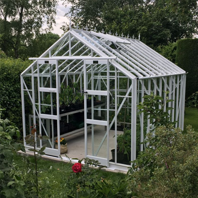 white aluminium 8x6 greenhouse in garden on slabs